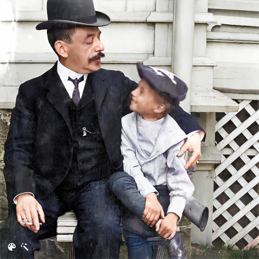 1897 n . Isä ja poika istumassa penkillä seinän vierustalla Kaivopuistossa (Läntinen Kaivopuisto, huvila numero 5). Helsingin kaupunginmuseo. Kuva on väritetty MyHeritagen In Colorilla